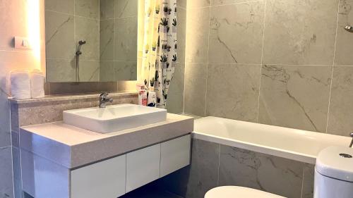 a bathroom with a sink and a tub and a toilet at The Astra 2bedroom apartment in Chiang Mai