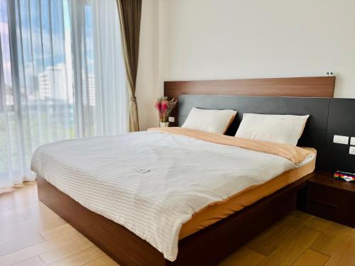 a bedroom with a large bed with a large window at The Astra 2bedroom apartment in Chiang Mai