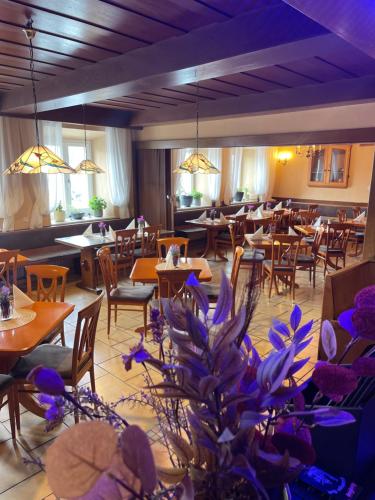 a restaurant with tables and chairs and purple flowers at Pilstinger Hof in Pilsting