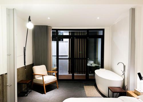 a bathroom with a tub and a chair and a bed at UNS B&B in Kaohsiung