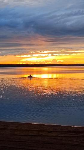 a boat on the water with the sunset in the background at Årsunda Strandbad in Årsunda