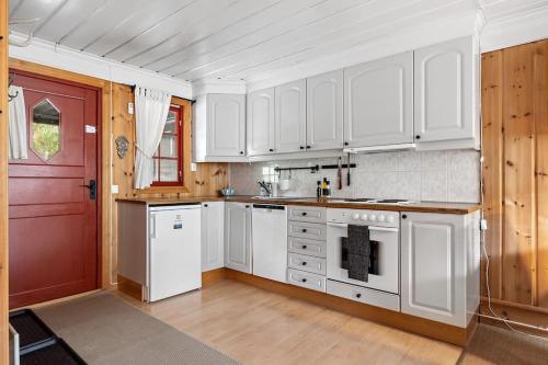uma cozinha com armários brancos e uma porta vermelha em Flott hytte i Vrådal rett ved alpinbakken em Vradal