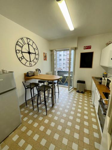 une cuisine avec une table et une grande horloge murale dans l'établissement Appartement Hyper Centre Place Kléber 66 m2, à Strasbourg