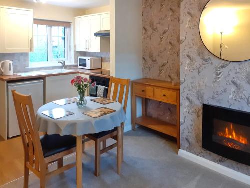 a kitchen with a table and a fireplace at End Cottage in Horncastle