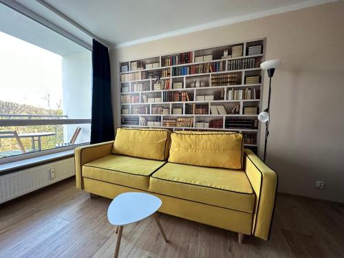 salon z żółtą kanapą i półką na książki w obiekcie Wczasowa Przystań w Ustroniu