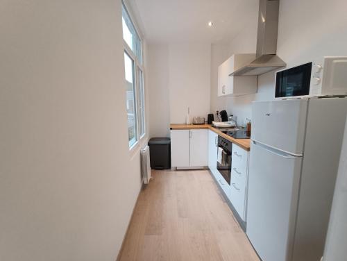 Il comprend une cuisine équipée d'appareils électroménagers blancs et d'un réfrigérateur blanc. dans l'établissement Blue Horizon - Appartement 4 pers, à Dunkerque