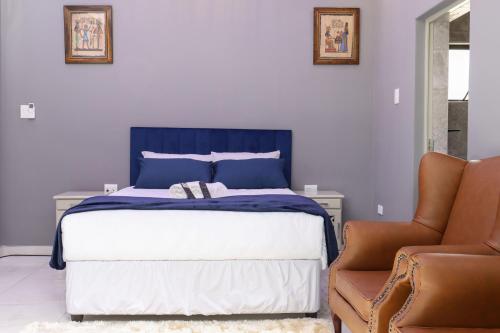 a bedroom with a blue and white bed and a chair at 235 LODGE in Durban