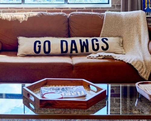 un sofá con una almohada Go Davis en una mesa de centro en UGA Penthouse Downtown Athens Walk To Stadium, en Athens