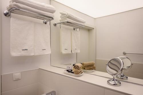 a white bathroom with a mirror and towels at LOCATION in Sofia