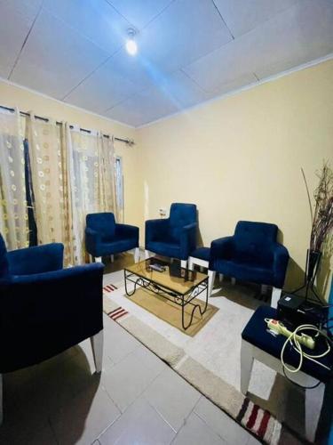 sala de estar con sillas azules y mesa en LNIMMO-LAGRACE-Studio calme avec internet illimité et forage, en Yaoundé