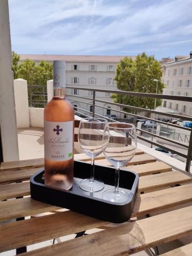 - une bouteille de vin et 2 verres à vin sur un plateau dans l'établissement les LOFTS de SAINT CLAIR Un balcon à TOULON CENTRE VILLE, marché provençal, 4CH avec bureau et connexions WIFI haut débit, CLIM, 5 smart TV, 2 salles d'eau, 2WC, 8 PAX max, tout à pied, à Toulon