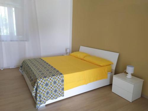 a bedroom with a bed with a yellow blanket and a night stand at Casa al tramonto...sunset lovers retreat in Lipari