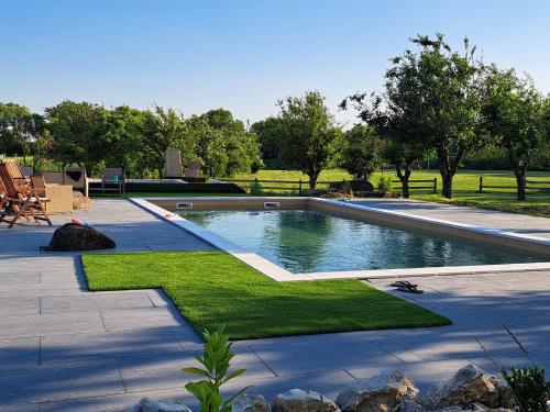 a swimming pool in a yard with grass and trees at Vidéki Ház in Tagyon