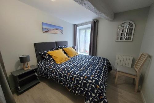 um quarto com uma cama com almofadas amarelas e uma cadeira em Gite Douar Armor le 28 em Dinan