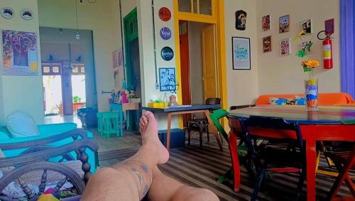 a person with their feet up in a room with chairs and tables at Hostel Recife Bar quartos climatizados das 22h às 6h in Recife