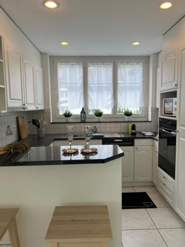 a kitchen with white cabinets and a black counter top at Wohnung „Perla Paradiso“ in Fluelen