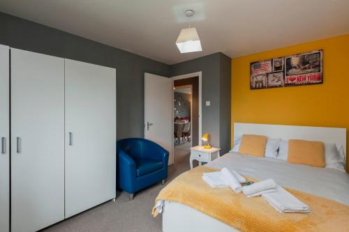 een slaapkamer met een bed en een blauwe stoel bij Cosy 2 BDR Flat with Free Parking close to Tower Bridge in Londen