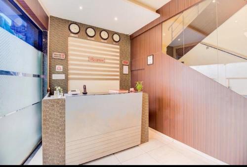 a lobby with a counter and clocks on the wall at Hotel Emerald Near T2 International Airport Mumbai in Mumbai