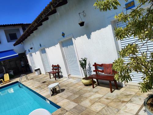 a patio with a pool and chairs and a house at Pousada Sol da Manhã in Guarujá