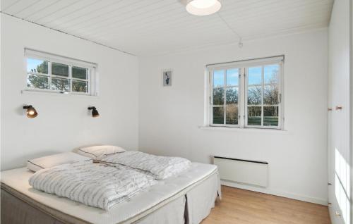 a bed in a white room with two windows at Awesome Home In Sams With Wifi And 3 Bedrooms in Sælvig