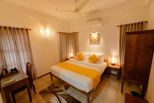 a bedroom with a large bed with yellow sheets at SeaCoast Inn FortKochi in Fort Kochi
