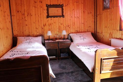 a bedroom with two beds and a wooden wall at Kuća za odmor Šegota in Brinje