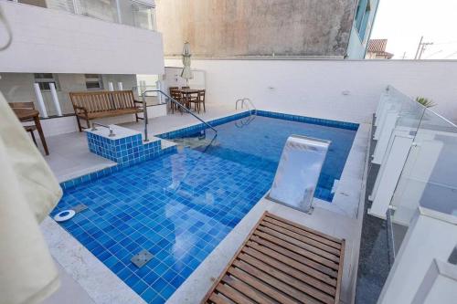 a large swimming pool with blue tiles in a building at Apto. a 40m da praia - Itanhaém. in Itanhaém