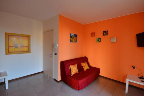 a red chair in a room with an orange wall at Le Palme Sona in Sona