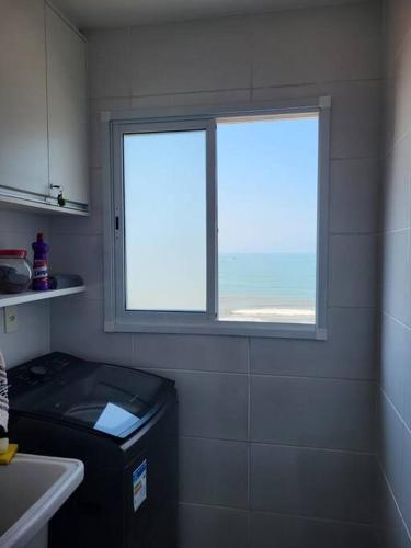 a bathroom with a window and a trash can in it at Apto. a 40m da praia - Itanhaém. in Itanhaém