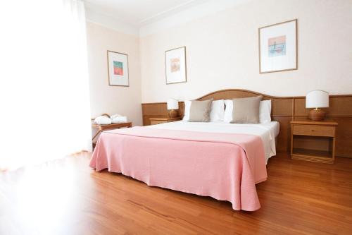 um quarto com uma cama grande e um cobertor rosa em Hotel Abbazia em Grado