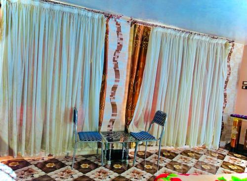 two chairs and a table in front of curtains at Nubian Dreams Guest House in Aswan