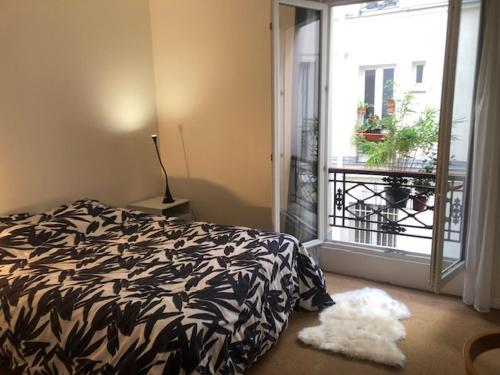 a bedroom with a black and white bed and a window at Chez Vero et Bruno in Paris