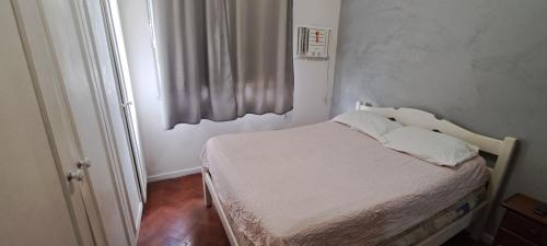 Un pequeño dormitorio con una cama con sábanas blancas y una ventana en Sofisticado Ambente A 1 cuadra de la playa Cod 1001, en Río de Janeiro