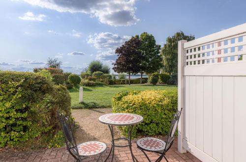 eine Terrasse mit einem Tisch und Stühlen neben einem Zaun in der Unterkunft Residenz am Seeufer in Waren (Müritz)