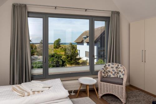 - une chambre avec un lit, une chaise et une grande fenêtre dans l'établissement Ostsee - Reetdachhaus Nr 43 "Ostseestern" im Strand Resort, à Heiligenhafen