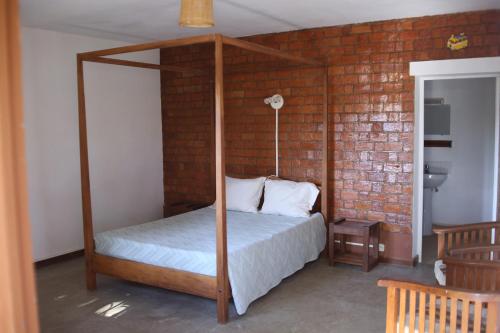 a bedroom with a four post canopy bed at Hotel Mahavelo in Antananarivo