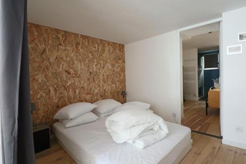 una camera da letto con letto, lenzuola e cuscini bianchi di Les Chatons - Résidence Guillaume Lacoste a La Bourboule