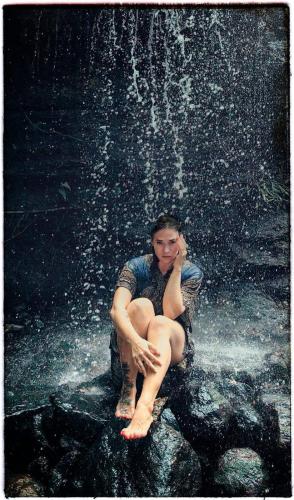 a person sitting on a rock under a waterfall at Chalet in the Jungle in Kaduwela