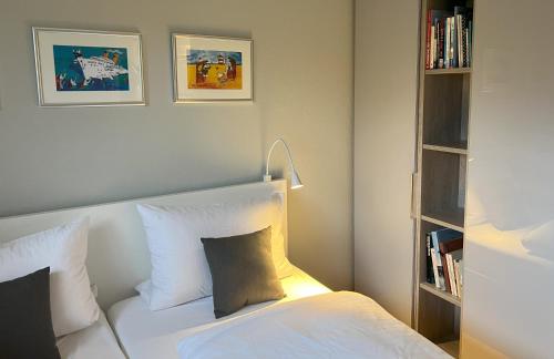 a bedroom with a white bed and a book shelf at Liebevoll auf Sylt in Tinnum