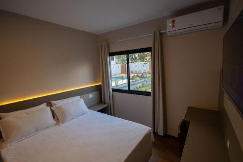a bedroom with a white bed and a window at Safa Hotel Foz in Foz do Iguaçu