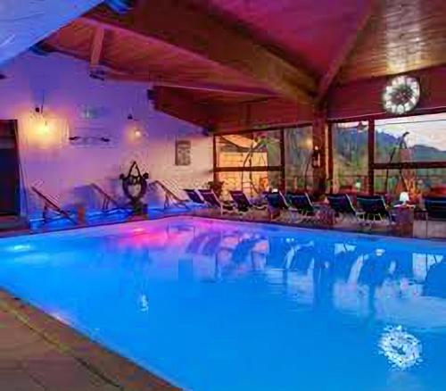 a large swimming pool with blue water in a building at Duplex « les 7 Marmottes », Les Balcons de Recoin in Chamrousse