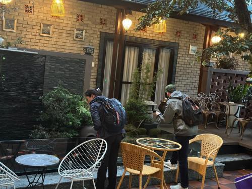 two people standing in a patio with chairs and tables at Nana Homestay & Villa in Hue