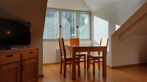 une salle à manger avec une table, des chaises et une télévision dans l'établissement Studio hyper centre lumineux et fonctionnel Luchon, à Luchon
