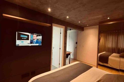 um quarto com uma cama e uma televisão na parede em Loft de Luxo na Vila Germânica em Blumenau
