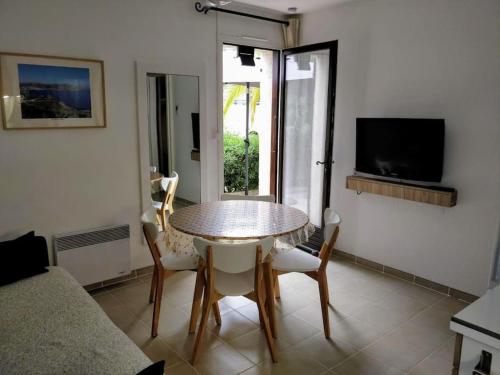 a living room with a table and chairs and a television at St Raphaël 37m2, piscine, wifi, commerces mer 5mn à pieds in Saint-Raphaël