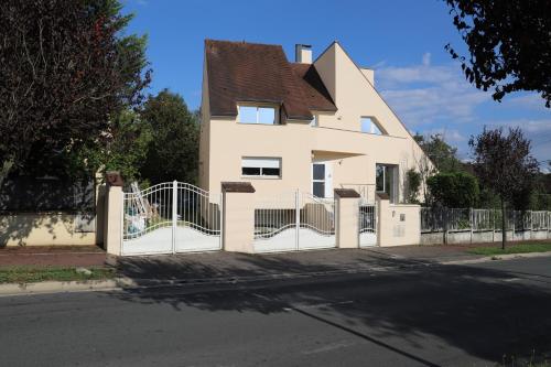 a white house with a gate and a fence at Le Parc du Moulin in Montfermeil