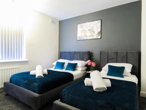 two beds in a room with blue and white at Tudors eSuites Four Bedroom House + Garden in Coventry