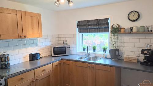 a kitchen with a sink and a microwave at Riverview Cottage in Halkirk