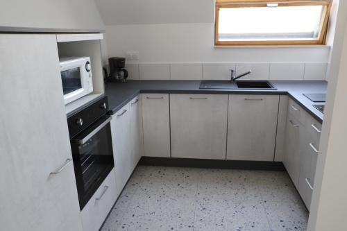 a white kitchen with a sink and a microwave at Le Parc du Moulin in Montfermeil