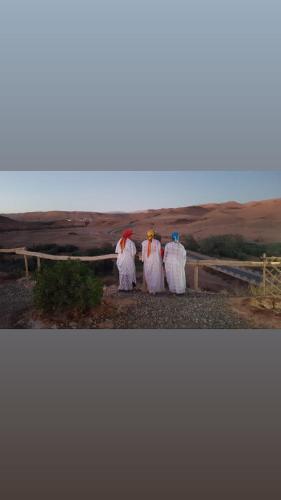 three people dressed in white standing in the desert at Tigmi Hamid Découverte des traditions et de la culture berbère in Aït Ben Haddou